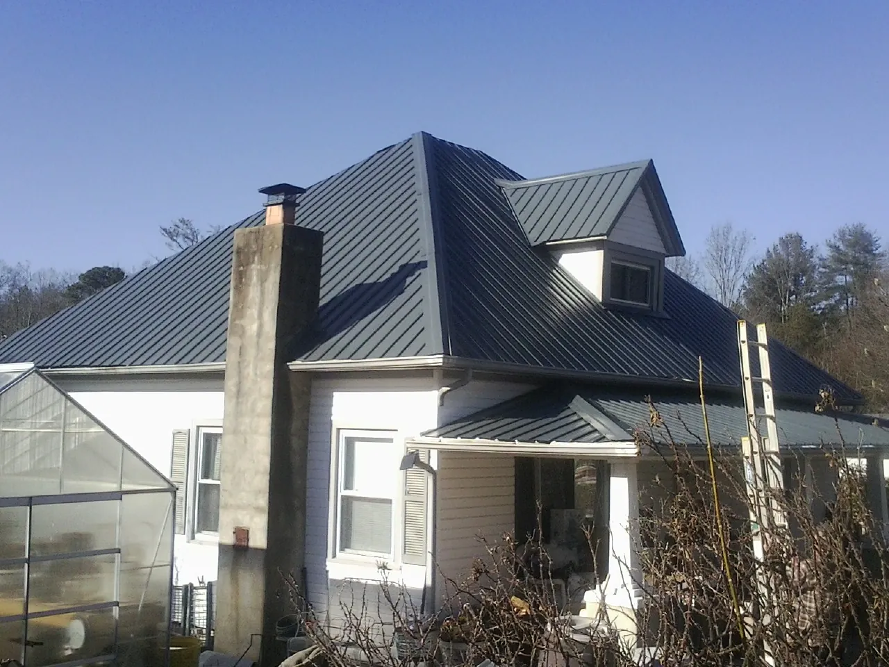 Dark blue standing seam metal roof on a white farmhouse with dormer — Slate & Tile Roof Repair by Roofing Brothers in Huntersville