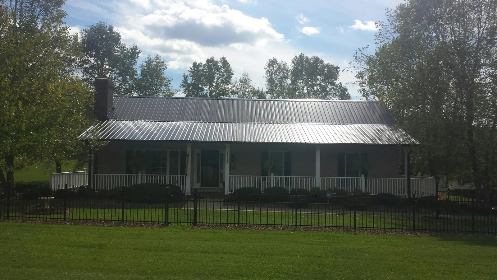 Gray metal roof on a brick ranch with a full width front porch — Gutter Guard Installation work by our crew in Huntersville