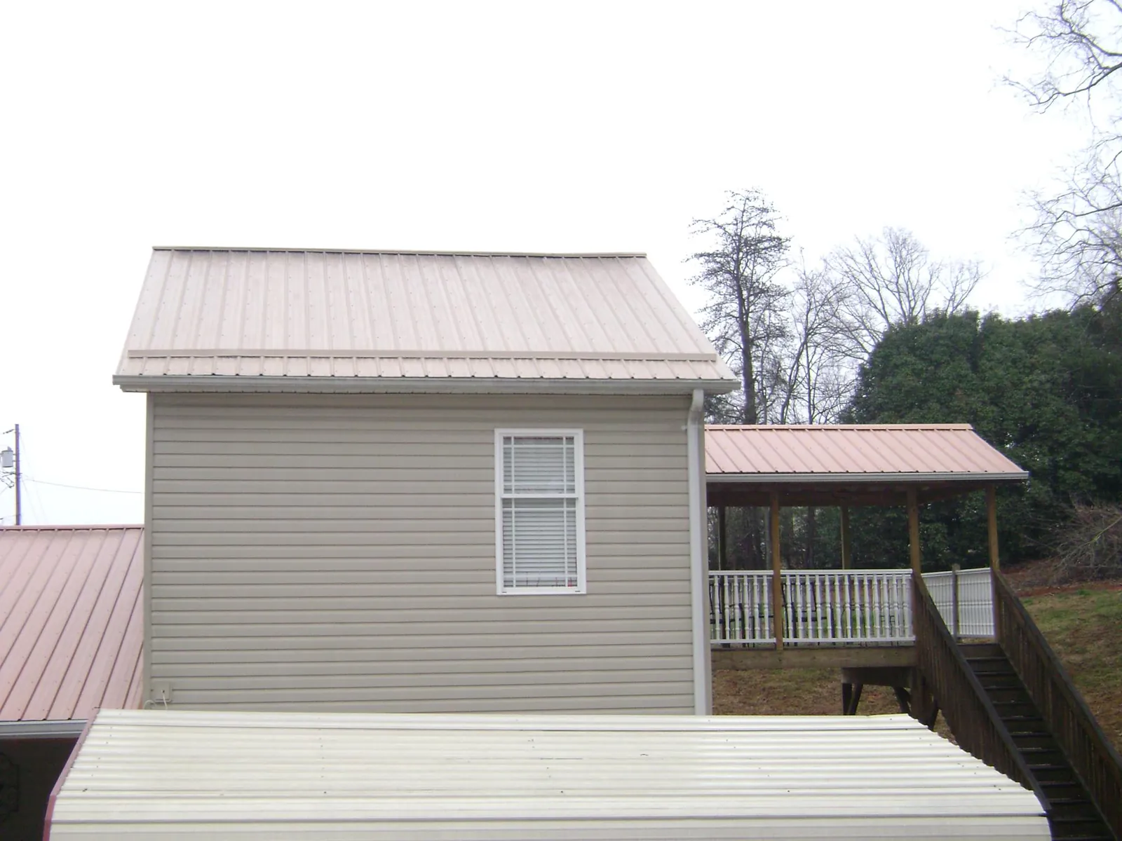 Tan metal roofs on a two story addition and attached porch, from a Roof Replacement job in Huntersville